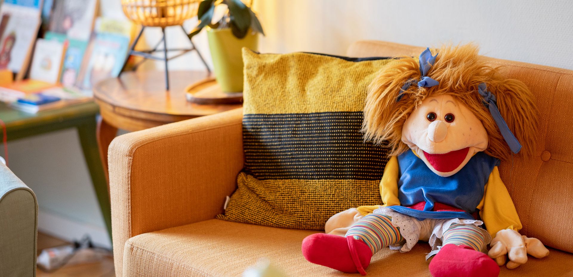 Foto einer Stoffpuppe, welche auf einem Sofa sitzt.