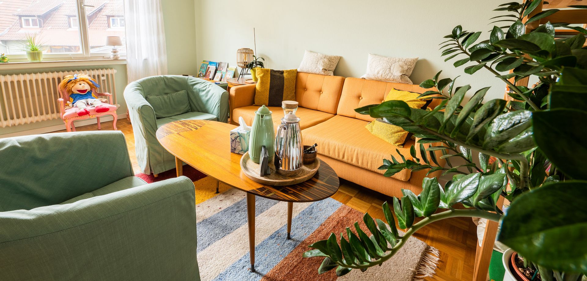Foto einer gemütlichen Sitzecke mit Sofa, Sessel und einem Tisch mit Teekannen und Wasserkaraffe.