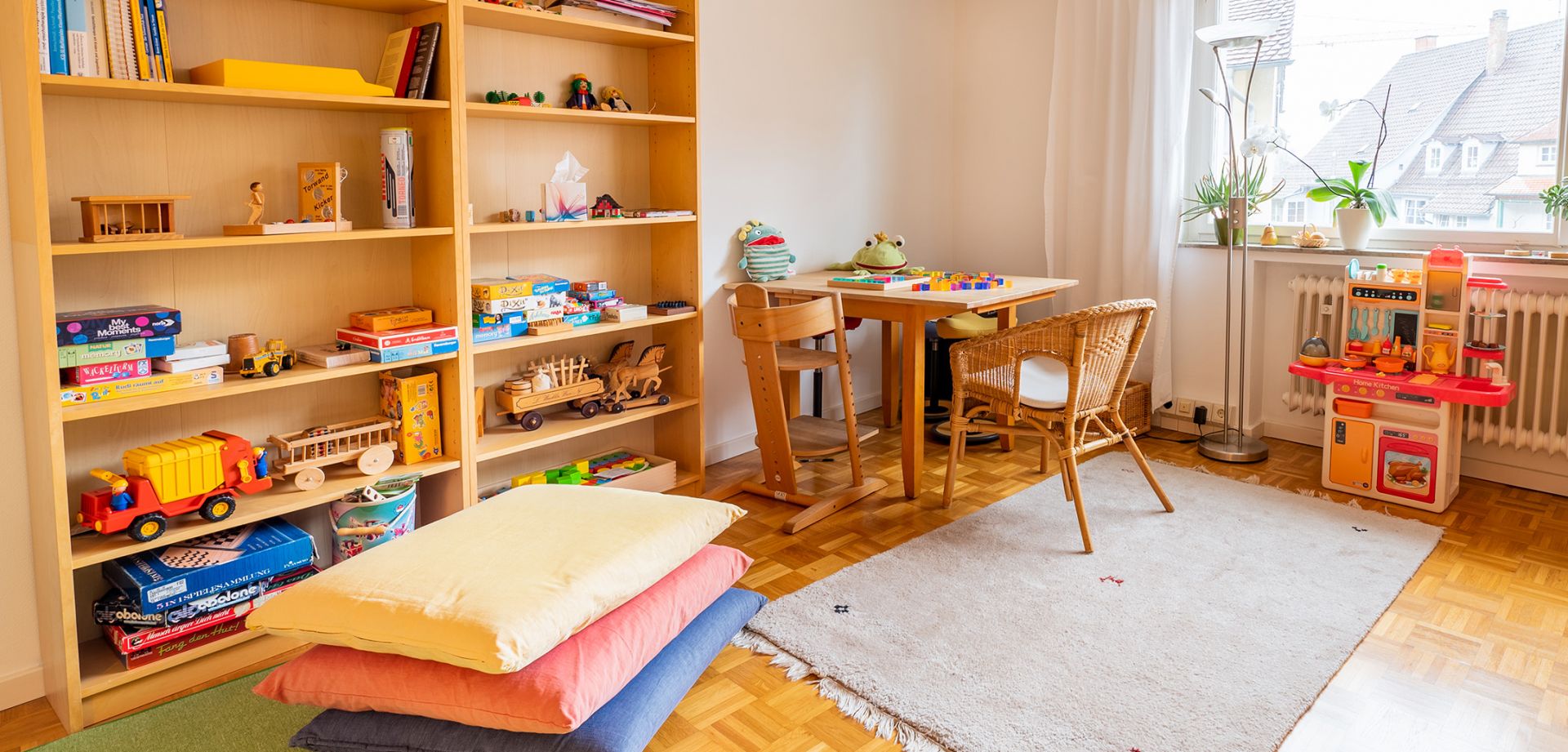 Foto einer Spielecke für Kinder mit einem Tisch und zwei Stühlen sowie verschiedenen Spielen.