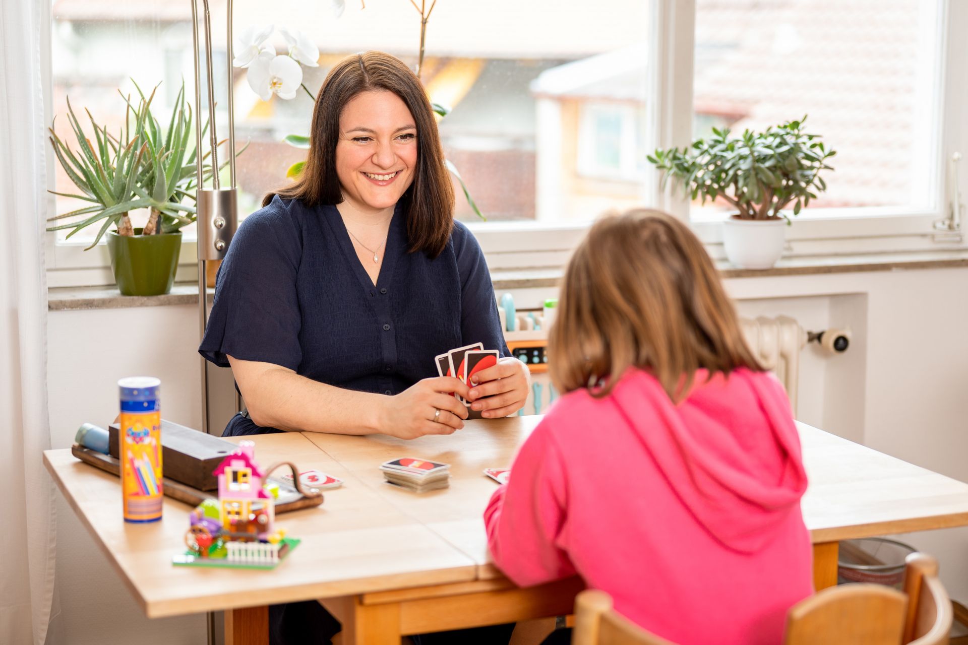 Foto von Sina Theodoridou, welche mit einem Kind Karten spielt.
